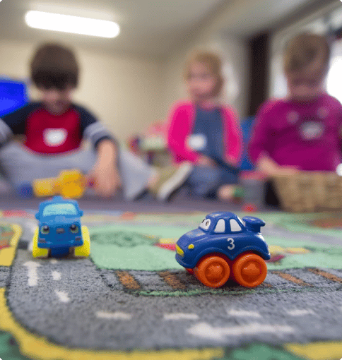 children playing with toy cars on rug
