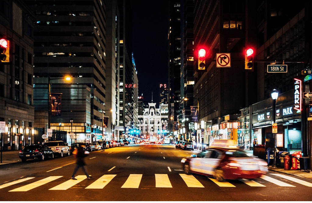 photo of pedestrian crossing busy Philadelphia road at night