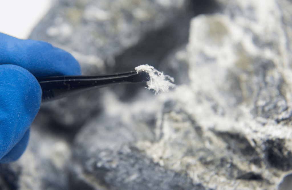 Photo of person with gloves grabbing asbestos fibers